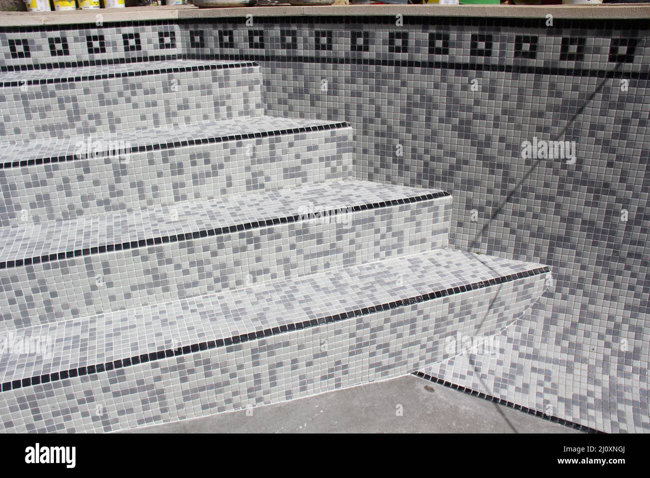 Des carreaux sont appliqués pour rénover une piscine. Image d'un groupe d'étapes de travaux réalisés par un spécialiste de la remise en état de la piscine. Banque D'Images