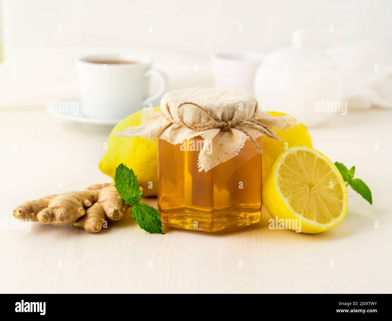 Moyens populaires pour traiter un rhume - un pot de miel, gingembre, menthe, citrons sur fond blanc, side view Banque D'Images