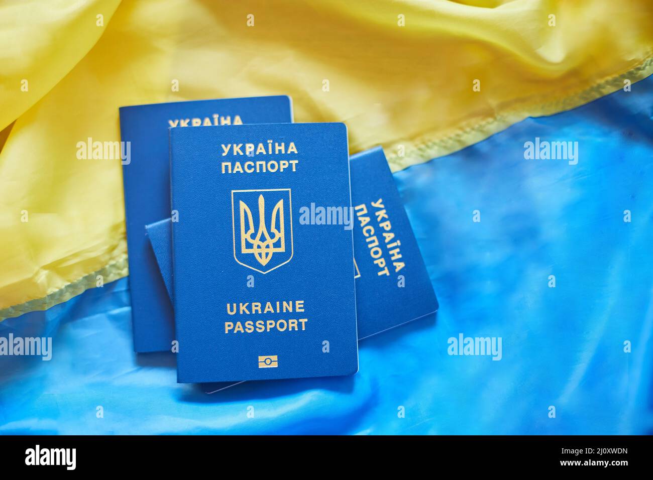 Trois passeports biométriques ukrainiens sur le drapeau de l'Ukraine, l'immigration parce que la guerre Banque D'Images
