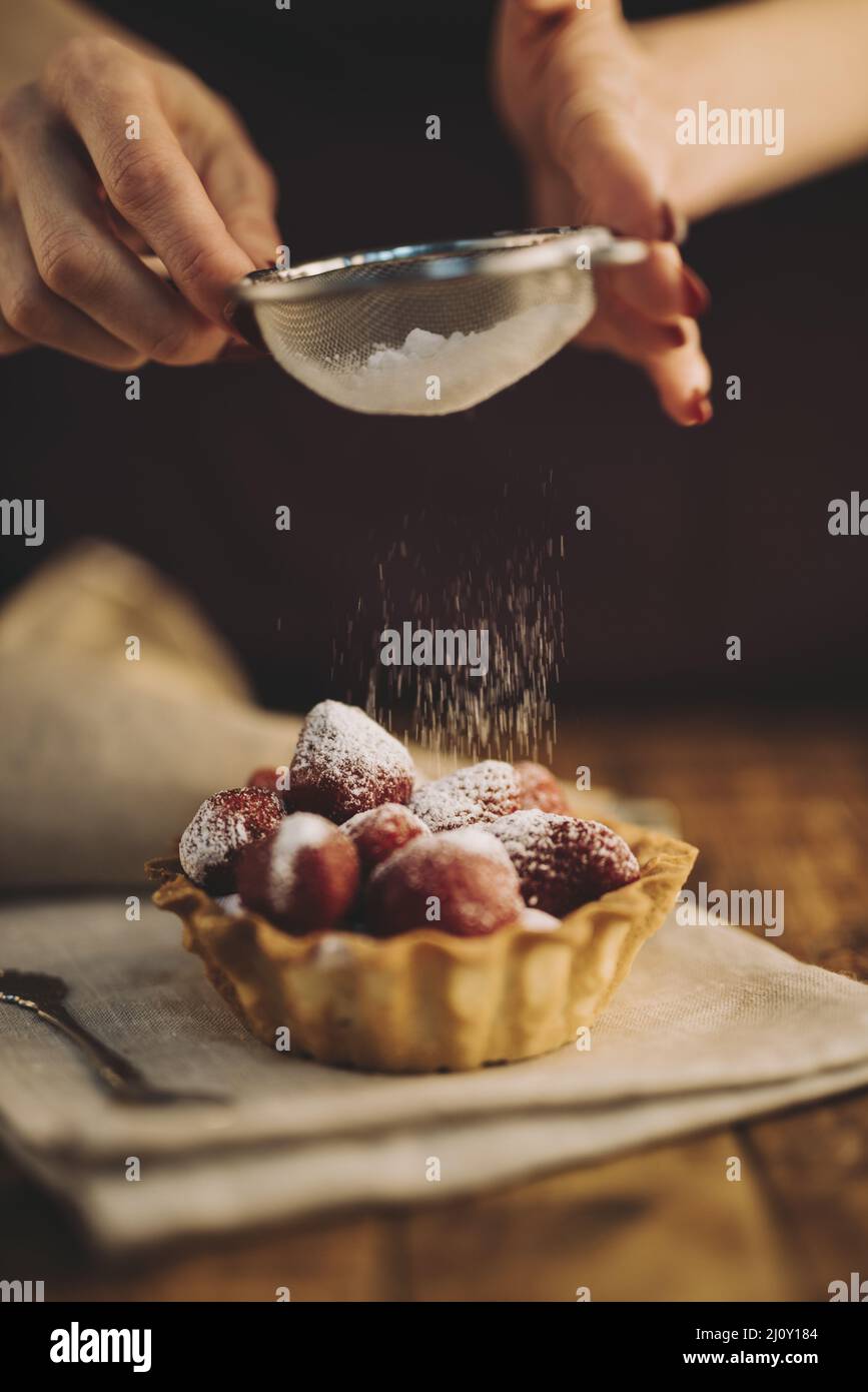 Femme dépoussiérant sucre poudre fraise tarte Banque D'Images