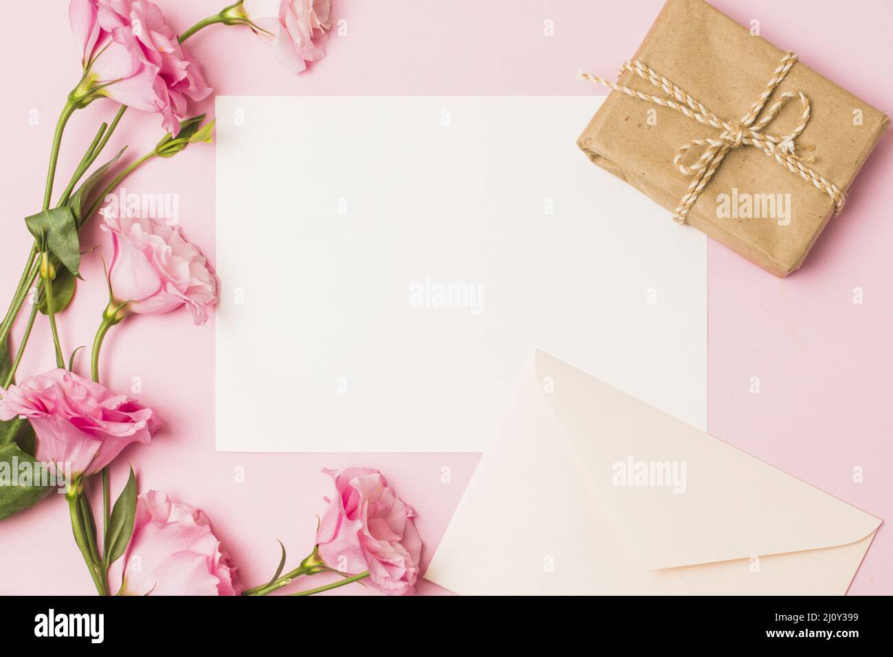 Papier vierge avec enveloppe rose frais fleur brun boîte cadeau emballage fond rose. Photo de haute qualité Banque D'Images