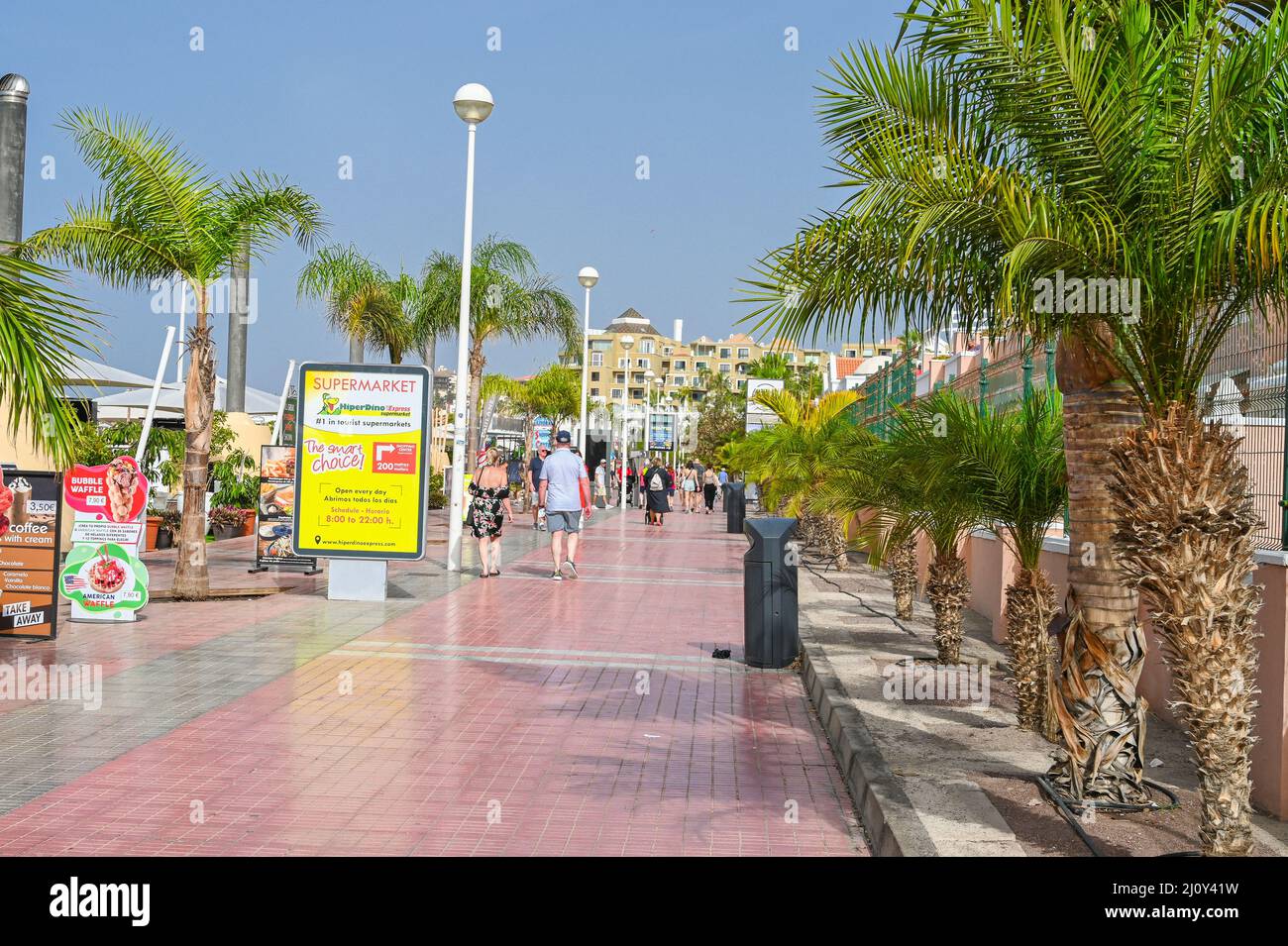 Un trottoir carrelé, promenade, le long du bord de mer à Costa Adeje, ligne avec des palmiers à l'ombre des touristes Banque D'Images