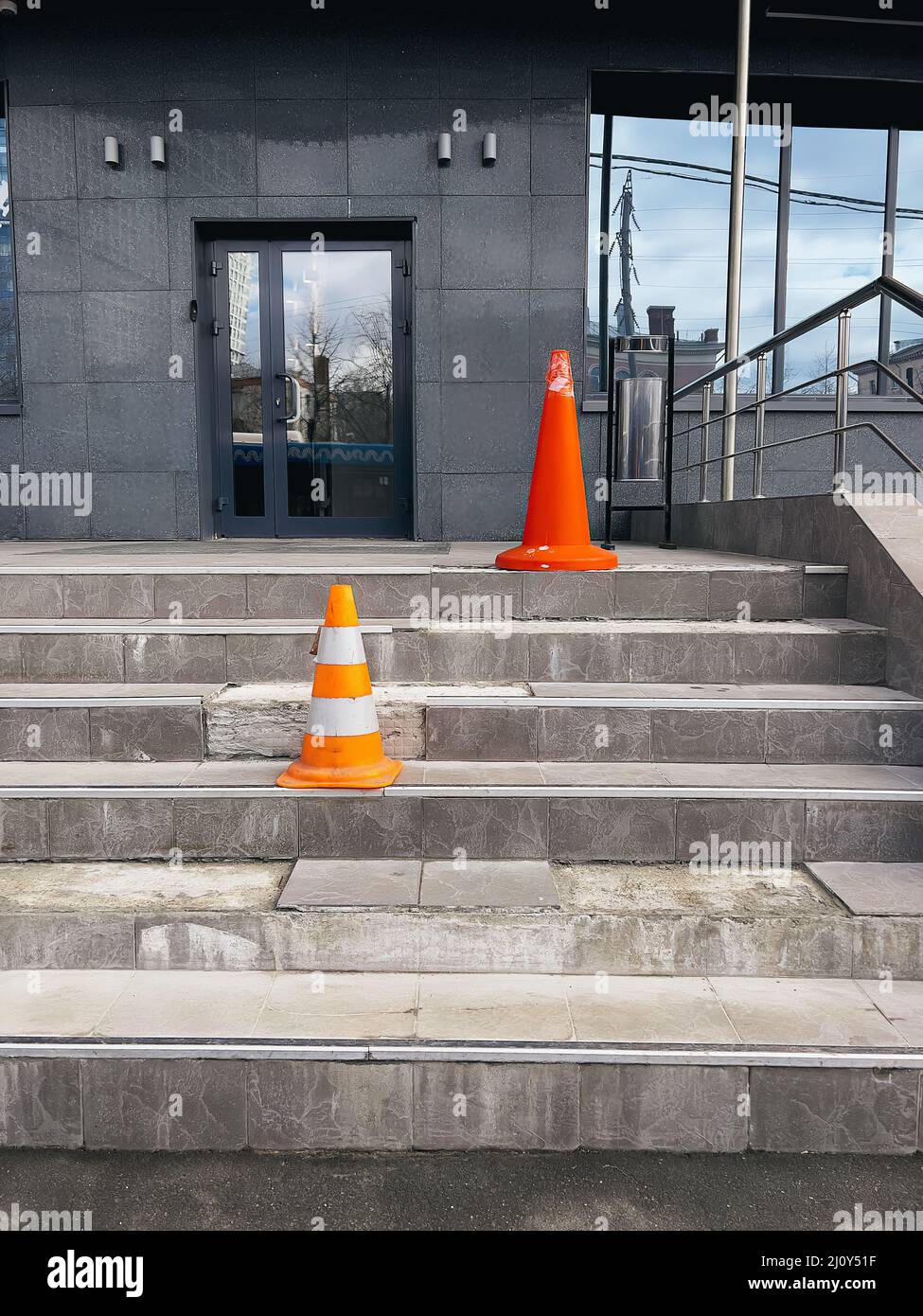 Des cônes de protection orange sur les marches cassées à l'entrée du bâtiment de bureau avertissent de tout danger. Banque D'Images