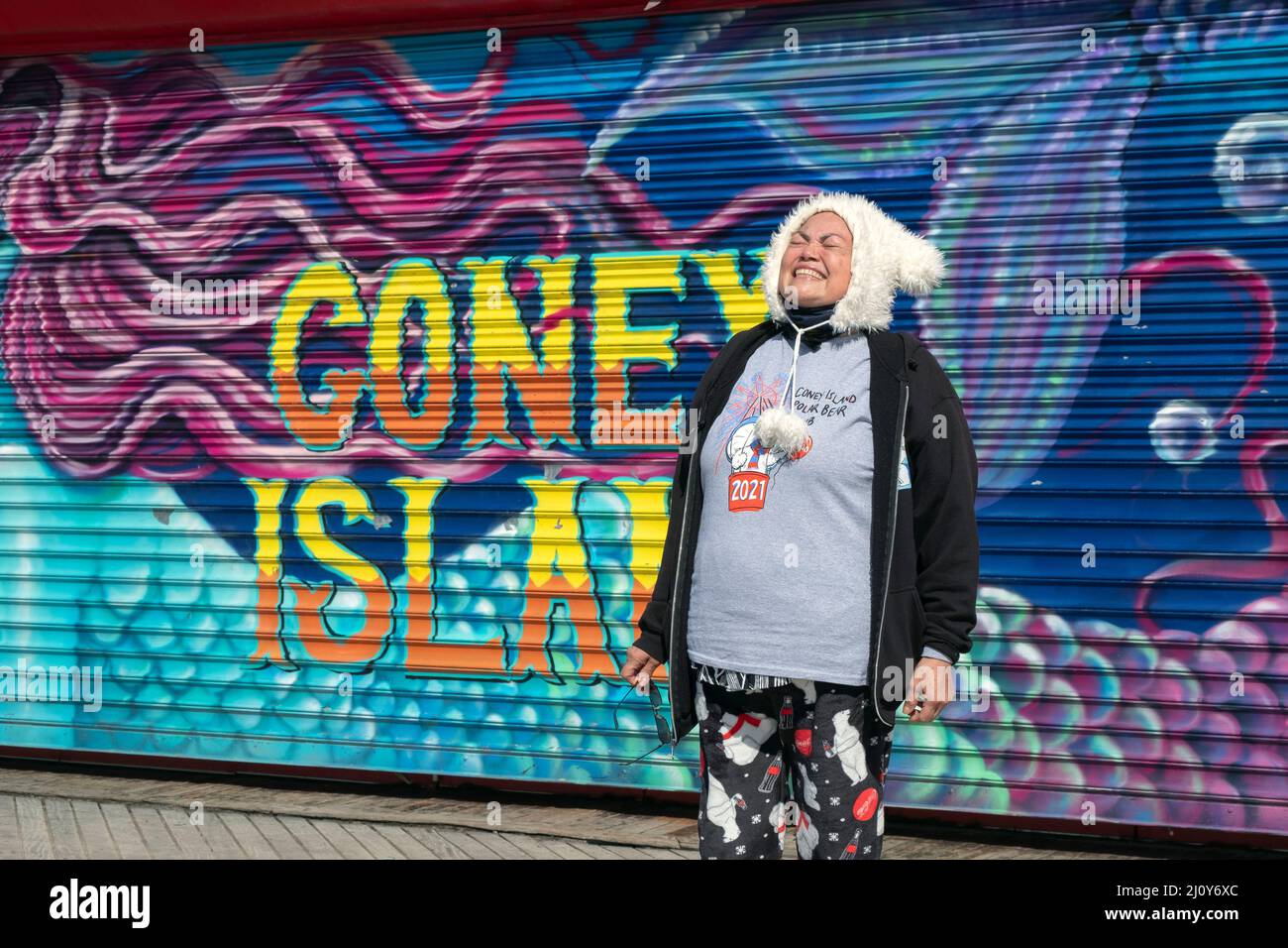 Le premier jour du printemps, une femme d'âge moyen pose sur la promenade de Coney Island avant la baignade hebdomadaire du club Polar Bear. À Brooklyn, New York. Banque D'Images