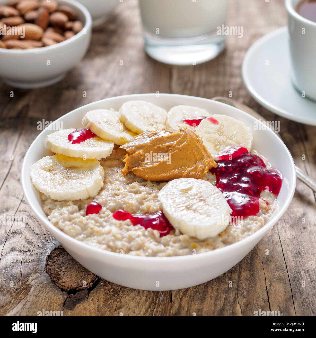 Petit-déjeuner sain le matin - le gruau avec des tranches de bananes, confiture de framboise et le beurre d'arachide. Vue de côté. Banque D'Images