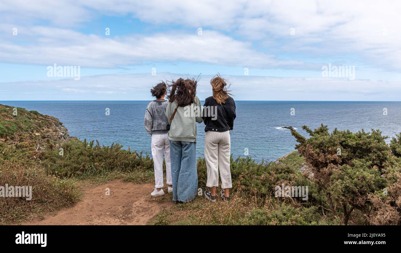 Trois filles aux cheveux longs se sont déplacées par le vent entre la montagne et la mer Banque D'Images