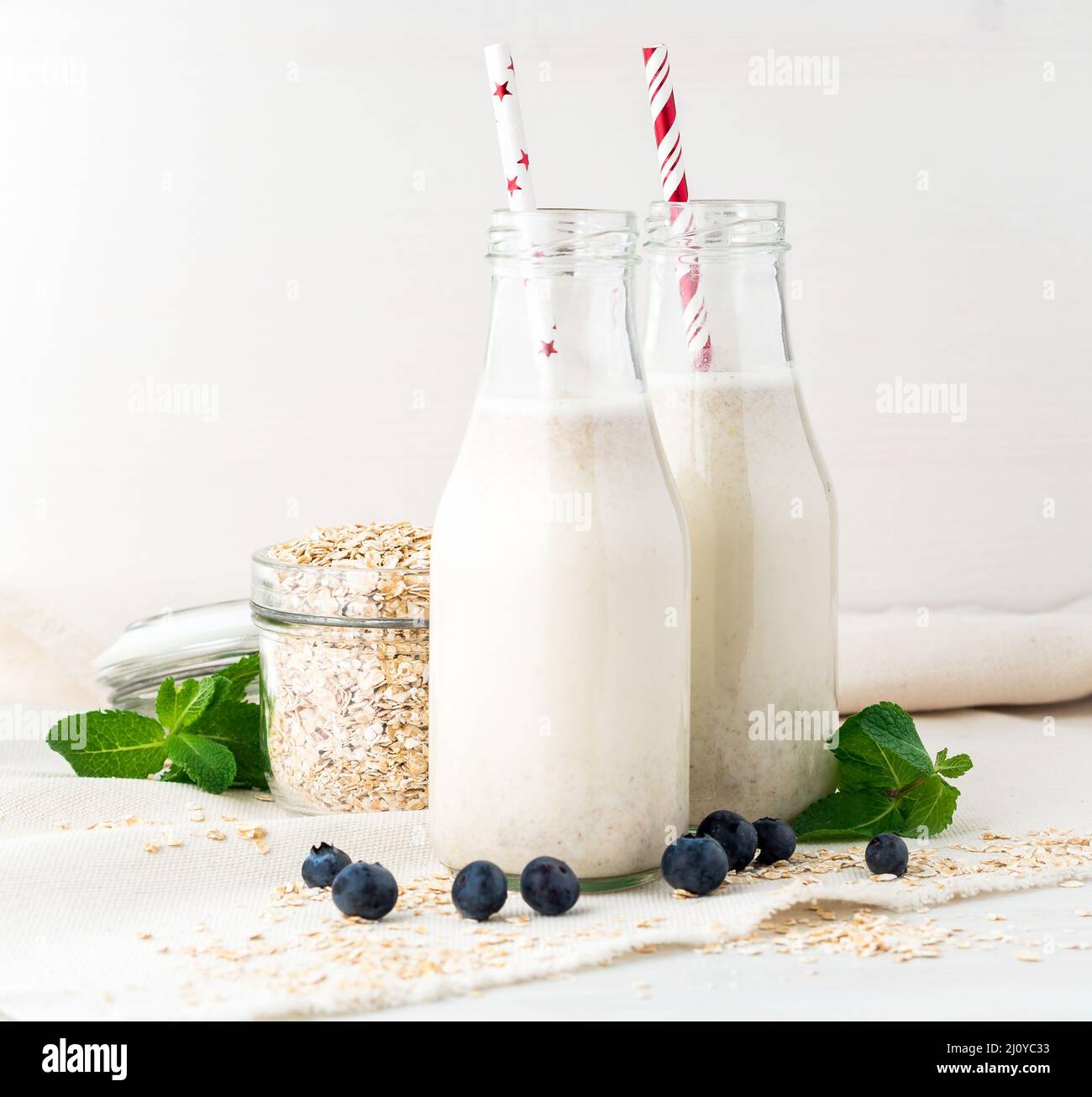 Smoothie aux flocons d'avoine, menthe pour un petit déjeuner sain. Lait d'avoine dans un biberon en verre avec tube sur fond blanc. Mise au point sélective Banque D'Images