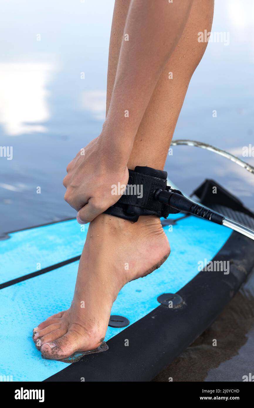 Une femme attache la laisse de surf sur sa cheville Banque D'Images