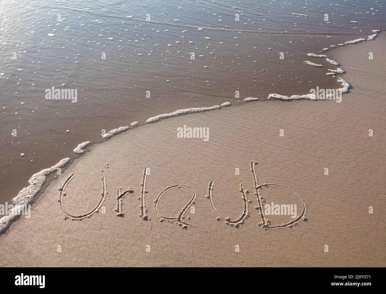 Mot 'HOLIDAY' en allemand écrit dans le sable Banque D'Images