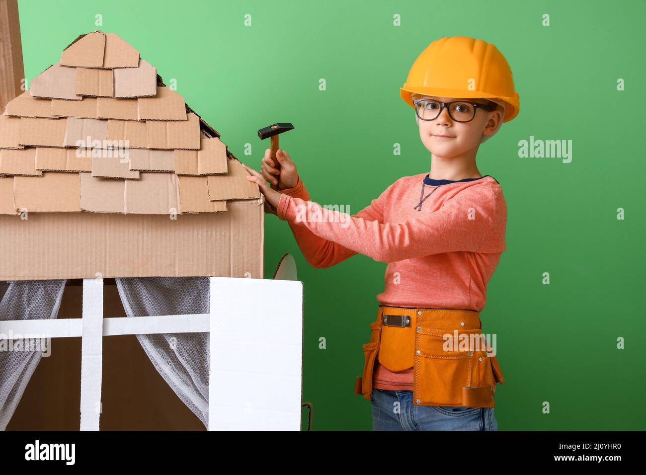 Drôle de petit constructeur jouant avec la maison de carton sur fond de  couleur Photo Stock - Alamy