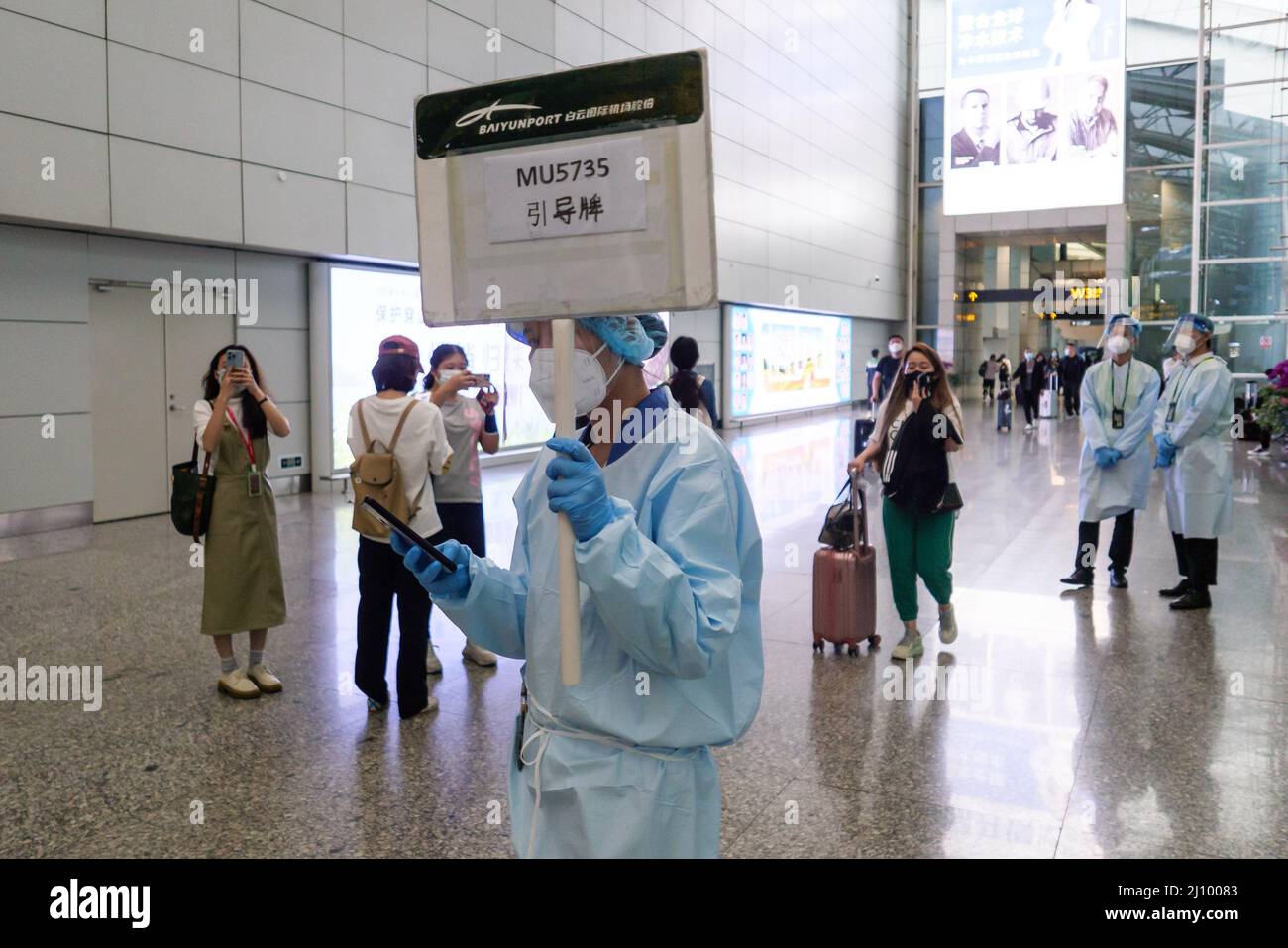 GUANGZHOU, CHINE - le 21 MARS 2022 - Un membre du personnel porte une pancarte indiquant que les passagers arrivent à la sortie de l'aéroport de Baiyun à Guangzhou, province de Guangdong, C. Banque D'Images