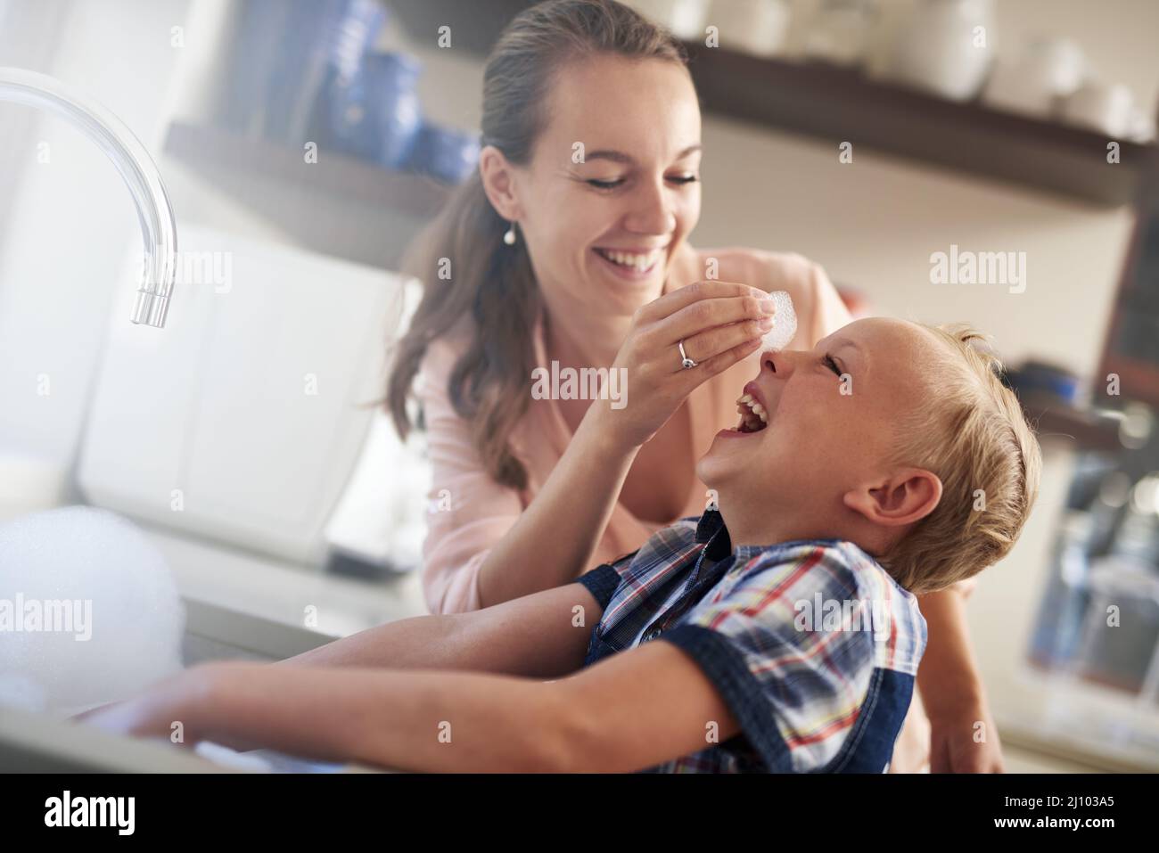 Le fait d'être stupide fait partie du plaisir. Photo d'une mère et d'un fils qui s'amusent tout en faisant des travaux ménagers. Banque D'Images