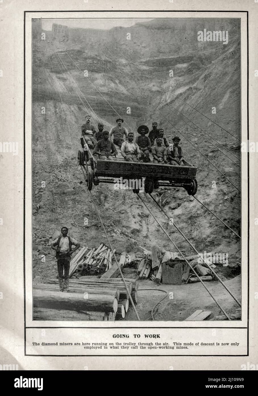 ALLER AU TRAVAIL. Les mineurs de diamants sont ici en train de courir sur le chariot à travers l'air. Ce mode de descente n'est maintenant employé que dans ce qu'ils appellent les mines à ciel ouvert. Photographie en noir et blanc du livre « Afrique du Sud; son histoire, ses héros et ses guerres » de William Douglas Mackenzie, et Alfred Stead, éditeur Chicago, Philadelphie : Monarch Book Company en 1890 Banque D'Images