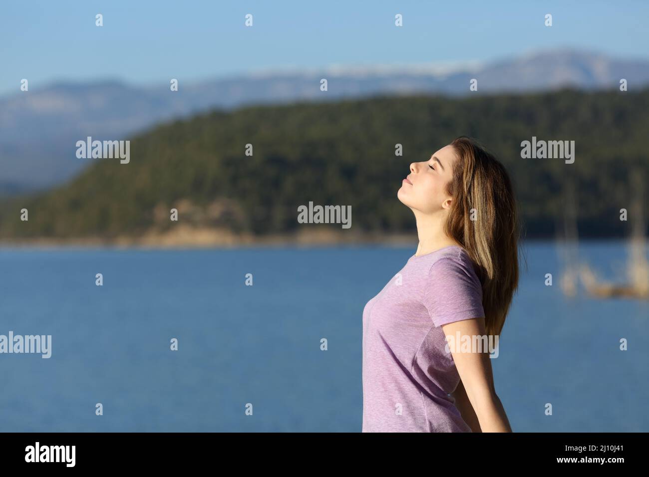 Vue latérale portrait d'une adolescente satisfaite respirant de l'air frais dans un lac Banque D'Images