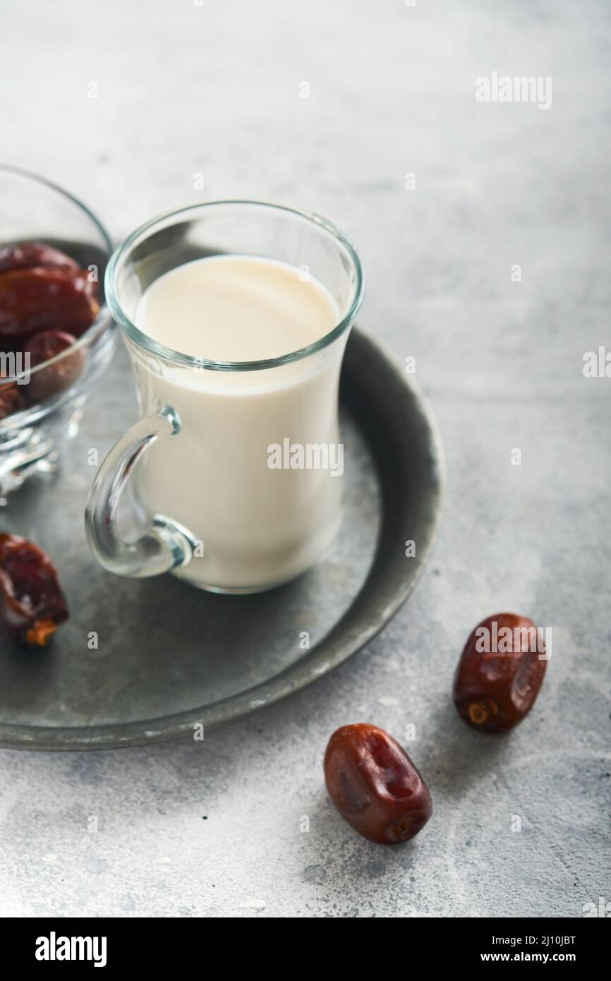Plats et boissons du Kareem de Ramadan. Plaque de dattes, verre de lait et branche de palmier sur fond gris clair. Un style de vie musulman juste. Placer pour tex Banque D'Images