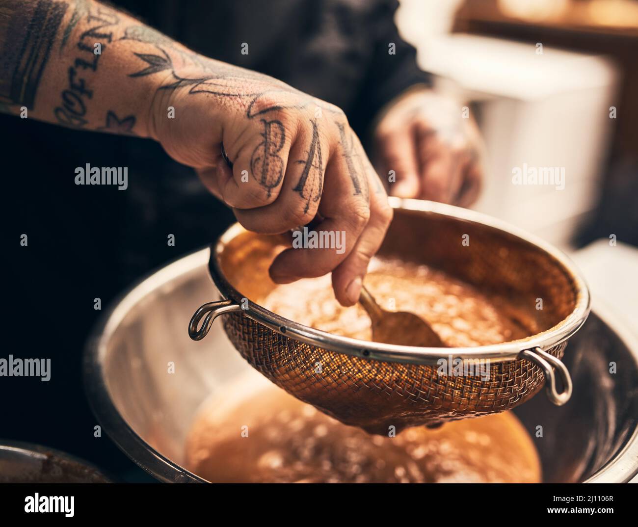 Ce plat est un défonce. Gros plan d'un chef méconnu tatoué les mains en train de mettre la nourriture dans un bol de la cuisine d'un restaurant. Banque D'Images
