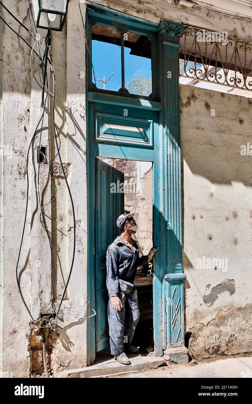 Employé local dans des vêtements de travail sales qui regardent hors de la  porte de l'ancien manoir. La Havane, Cuba Photo Stock - Alamy