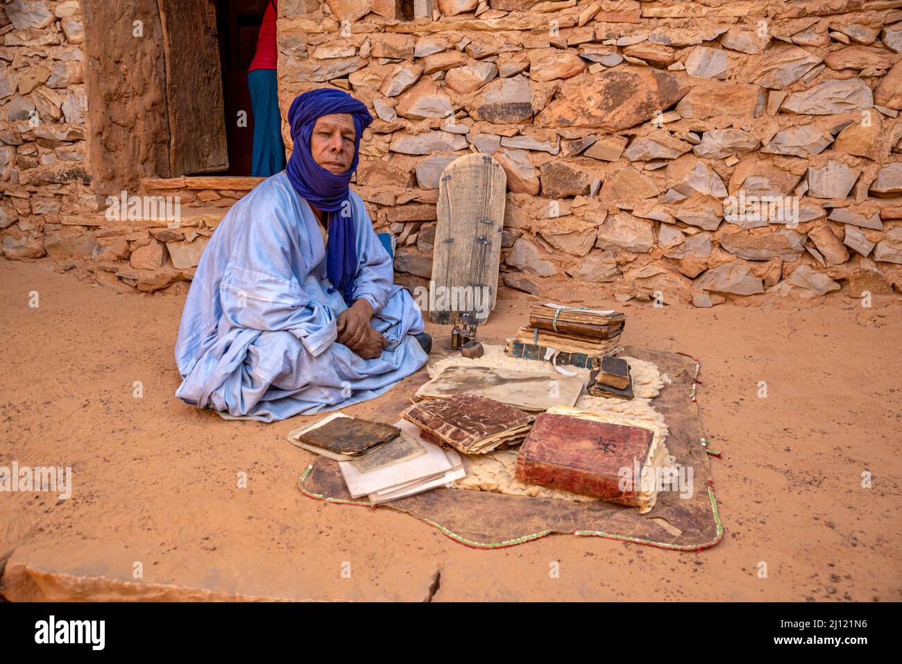 Homme mauritanien avec le boubou bleu traditionnel et le turban et de vieux livres islamiques dans une ancienne bibliothèque, Chinguetti, Mauritanie Banque D'Images