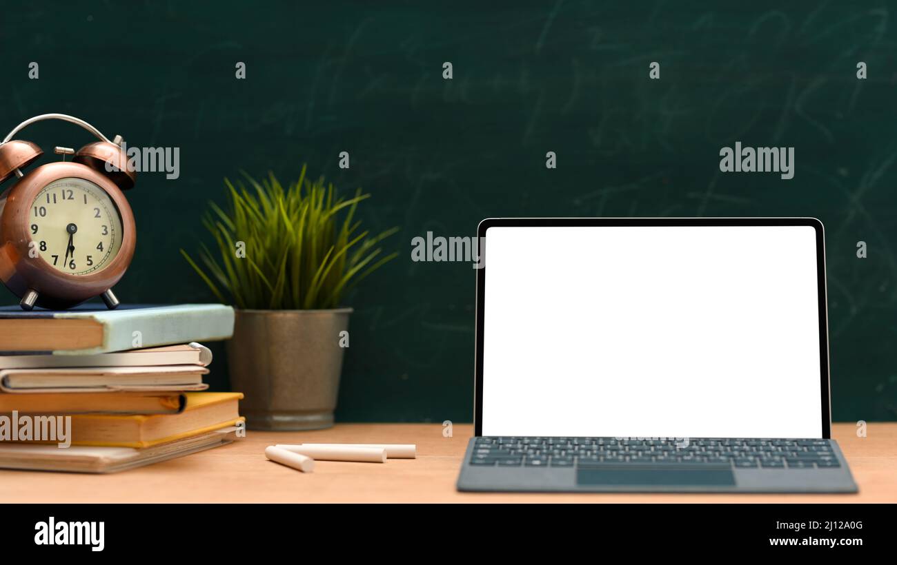 Table d'école vintage avec maquette d'écran blanc pour ordinateur portable,  pile de livres, horloge vintage et plante de décoration sur table en bois  sur fond de tableau vert Photo Stock - Alamy