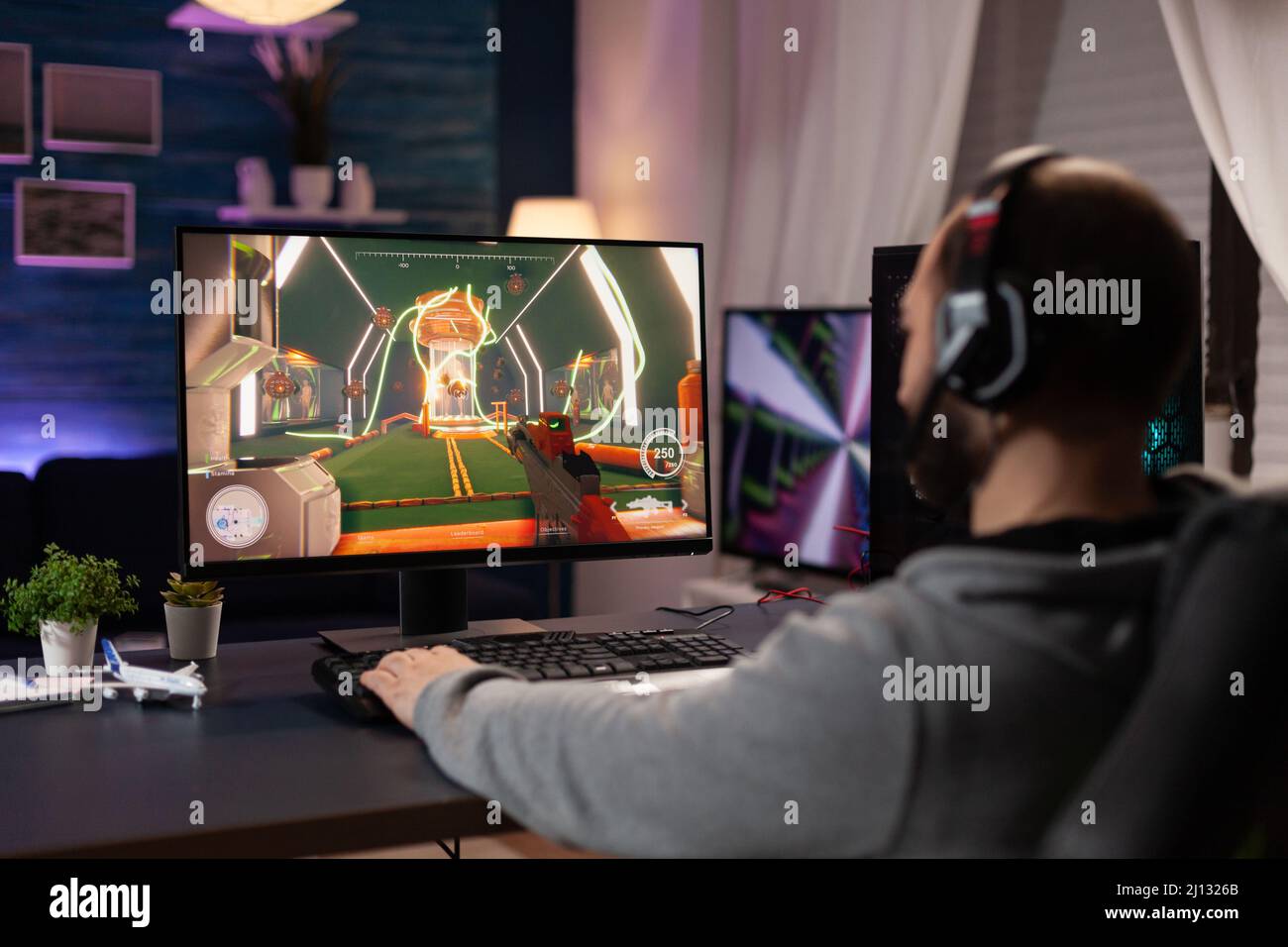 Adulte avec casque jouant à des jeux vidéo sur un ordinateur. Homme portant  un casque, utilisant le clavier et le tapis de souris pour jouer à des jeux  vidéo en ligne sur