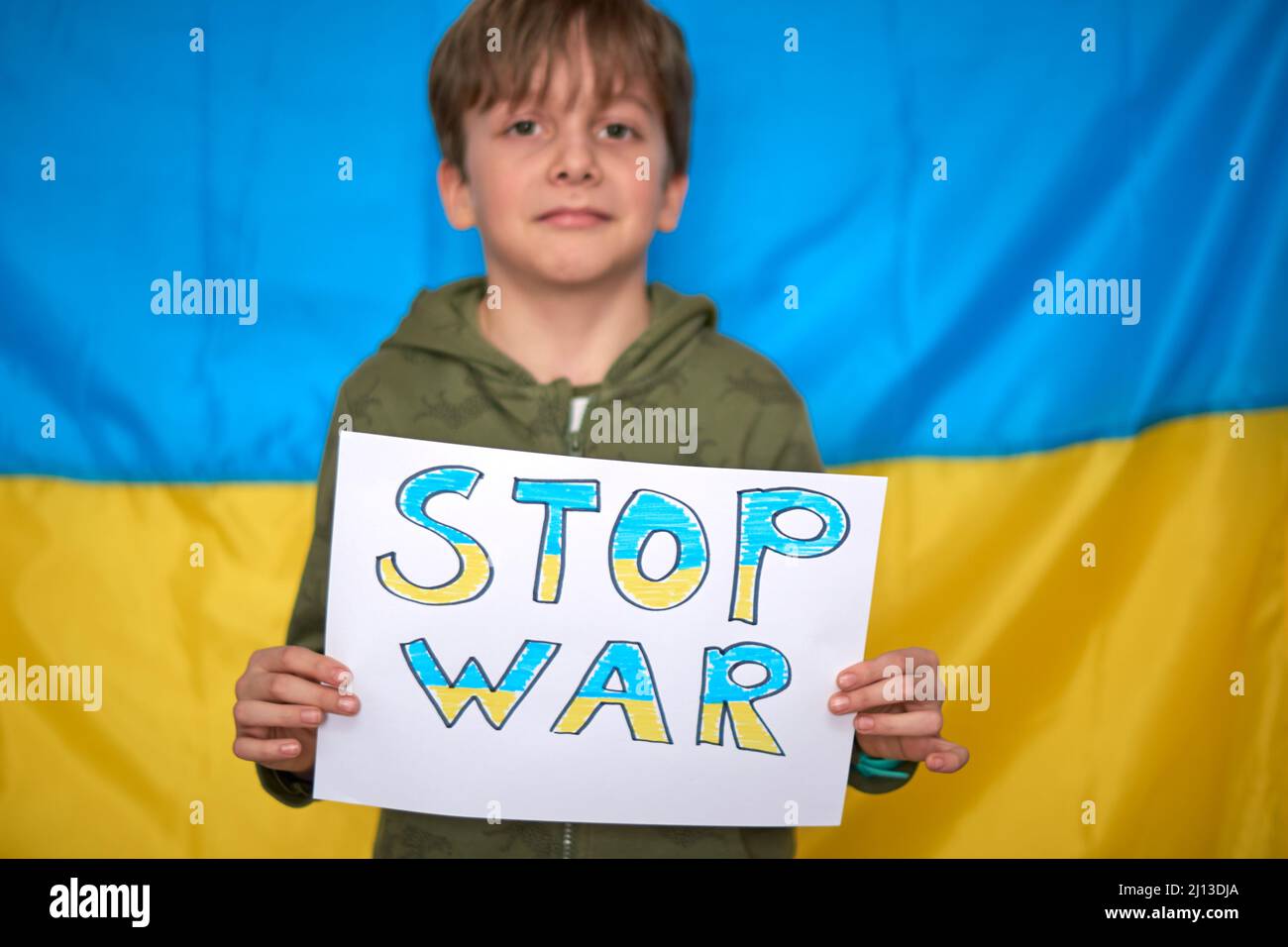 Mains de garçon tenant une bannière jaune-bleu sur fond de drapeau ukrainien. Les enfants soutiennent l'Ukraine, arrêtent la guerre, restent avec le hashtag de l'Ukraine Banque D'Images