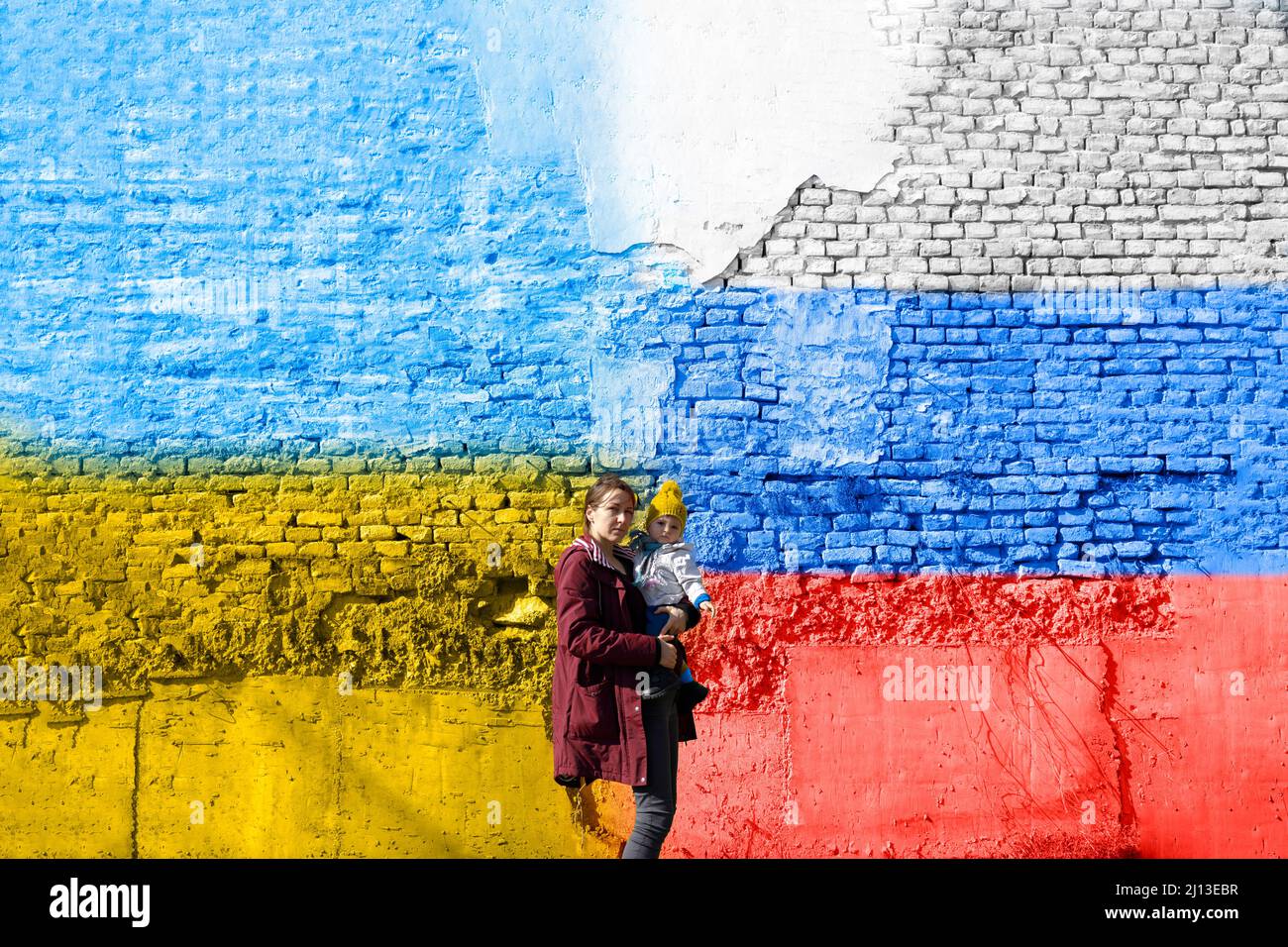 Une femme avec son enfant devant un mur peint en ukrainien et russe drapeau-trêve concept Banque D'Images