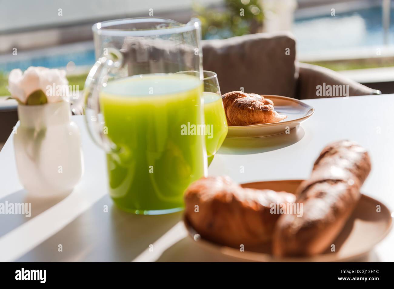 Petit déjeuner sain servi sur une table en bois dans l'espace avec fenêtre et lumière naturelle avec yaourt et smoothie vert dans des verres et un pot en verre, pain haché Banque D'Images