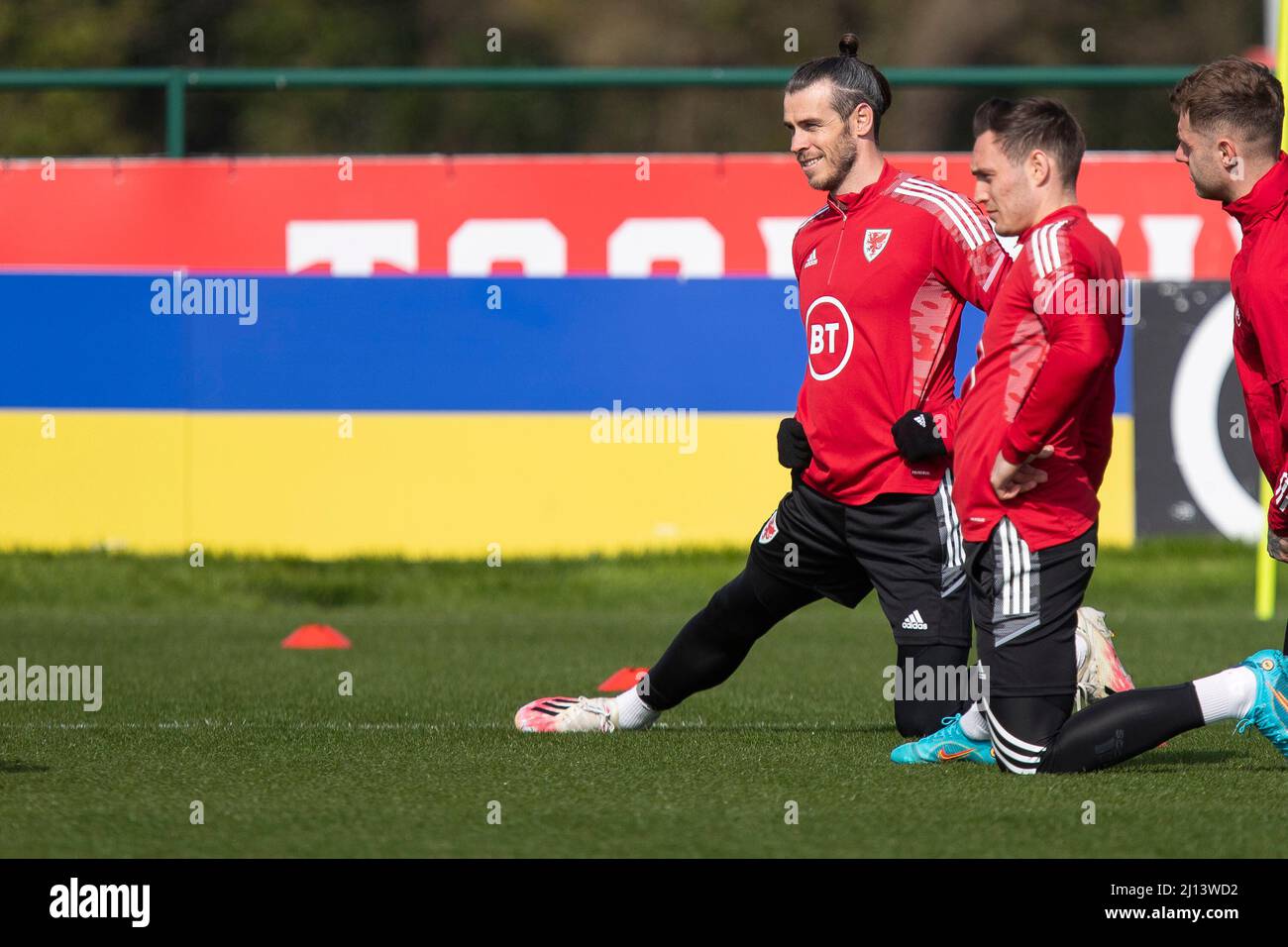 Hensol, pays de Galles, Royaume-Uni. 22nd mars 2022. Gareth Bale et Connor Roberts s'étirent devant une palissade montrant les couleurs du drapeau ukrainien lors de l'entraînement de l'équipe nationale de football du pays de Galles à Vale Resort avant le match de demi-finale de la coupe du monde 2022 du côté contre l'Autriche. Crédit : Mark Hawkins/Alay Live News Banque D'Images