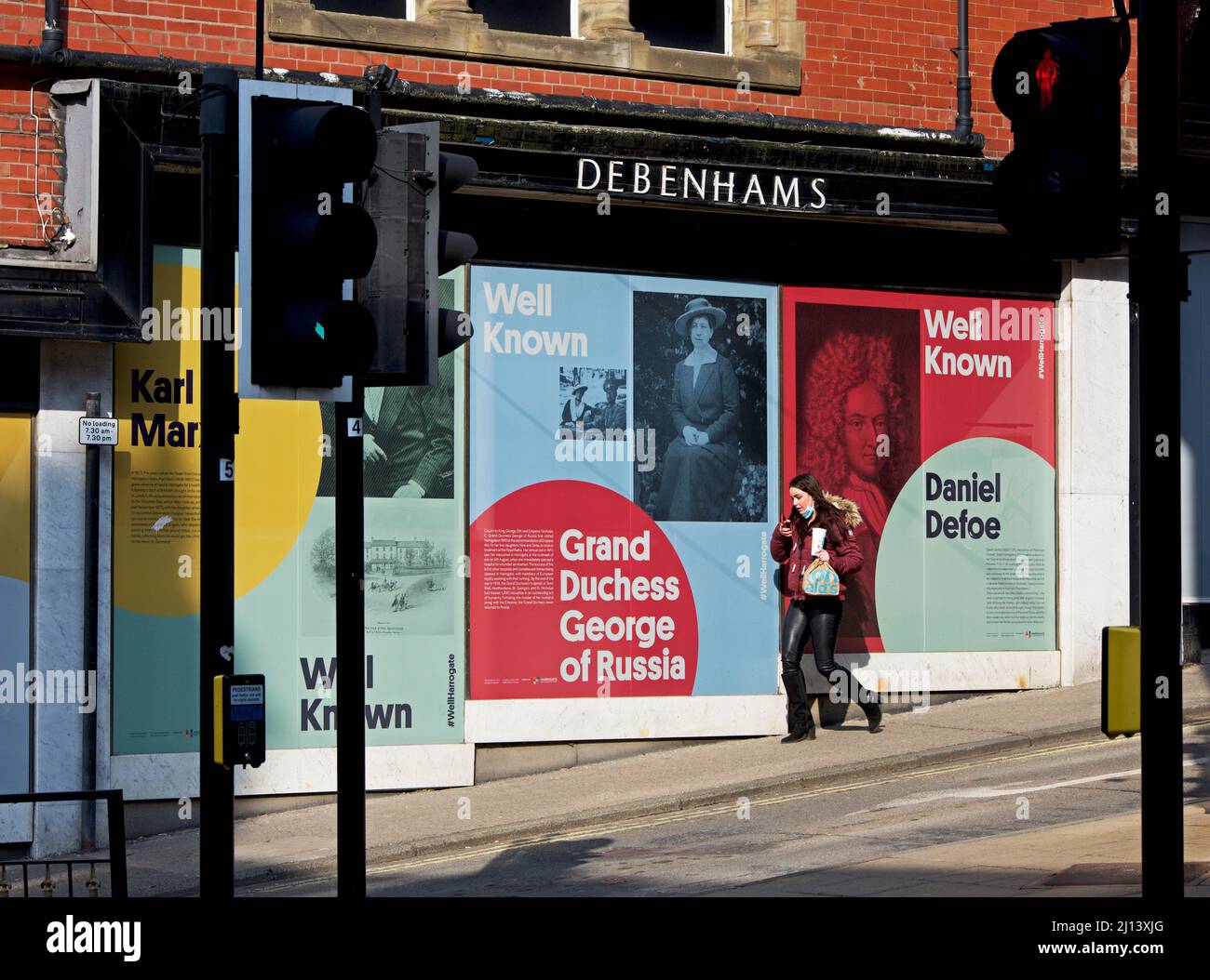 Jeune femme passant devant la succursale de Debenhams - maintenant hors des affaires - Harrogate, North Yorkshire, Angleterre Royaume-Uni Banque D'Images