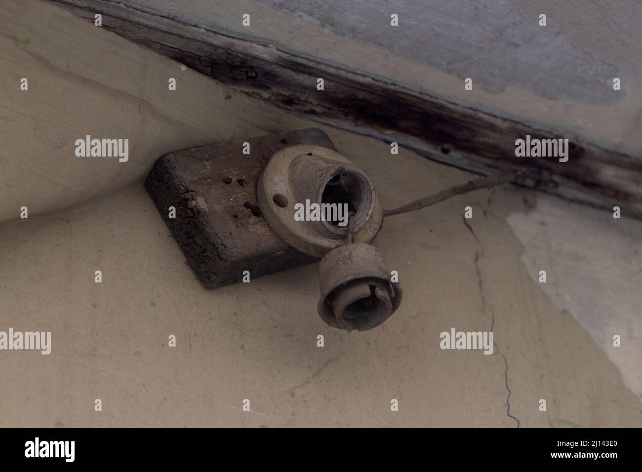 Ancien support de lampe endommagé sans ampoule sur un mur fissuré Banque D'Images