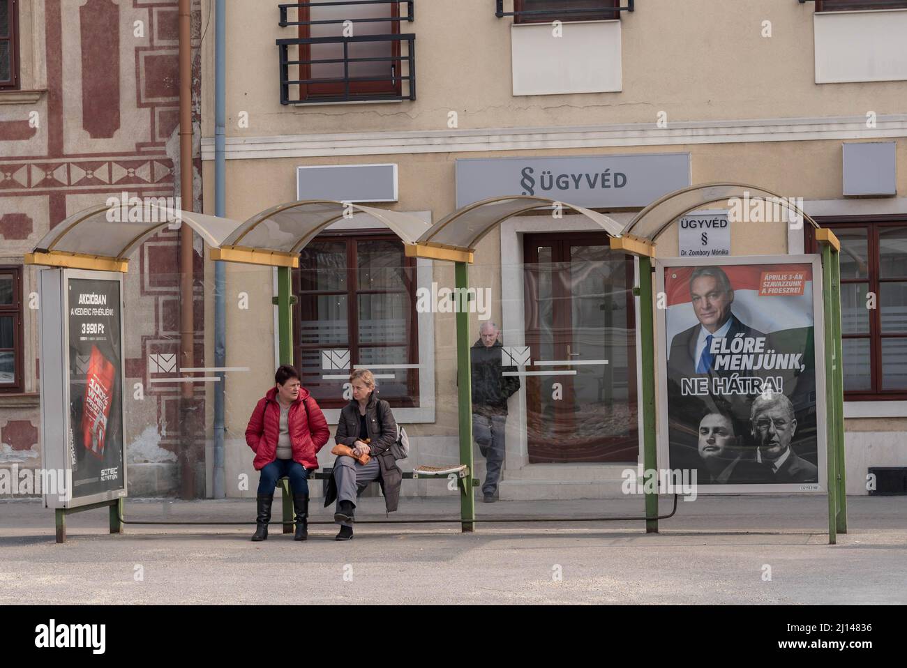 Mosonmagyarovar, Hongrie. 18th mars 2022. Un couple attend un arrêt de bus avec un panneau d'affichage des élections pour le Premier ministre hongrois Viktor Orban du parti Fidesz dans la rue. Mosonmagyarovar est la ville du nord-ouest de la Hongrie située à environ 160 kilomètres de la capitale hongroise Budapest. Peter Marki-Zay défiera le Premier ministre Viktor Orban lors des prochaines élections législatives, qui auront lieu le 3rd avril 2022. (Credit image: © Tomas Tkacik/SOPA Images via ZUMA Press Wire) Banque D'Images