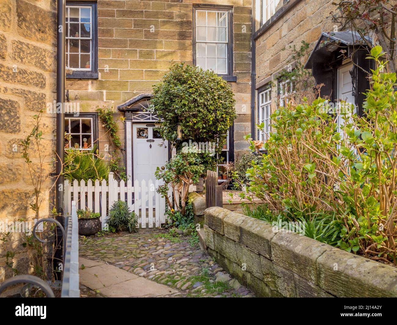 Maison traditionnelle en pierre avec clôture de piquetage blanche, située dans une ruelle étroite dans la vieille ville de Robin Hoods Bay, dans le North Yorkshire. Banque D'Images