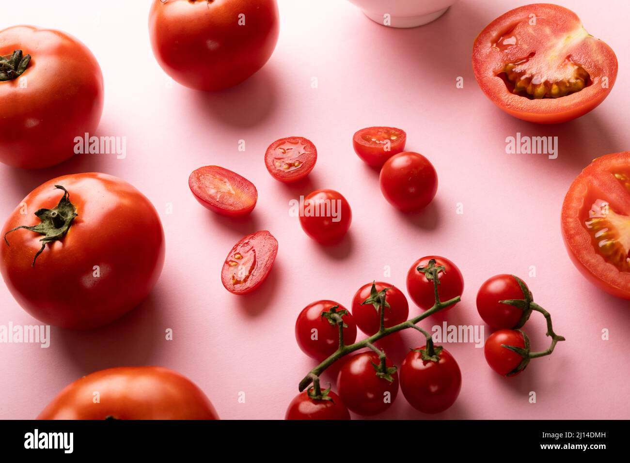 Vue en grand angle des tomates fraîches et des tomates cerises sur fond rose Banque D'Images