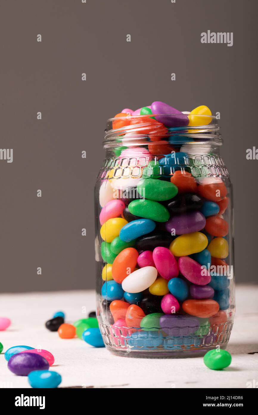 Gros plan de bonbons multicolores dans des pots en verre sur fond gris avec espace de copie Banque D'Images