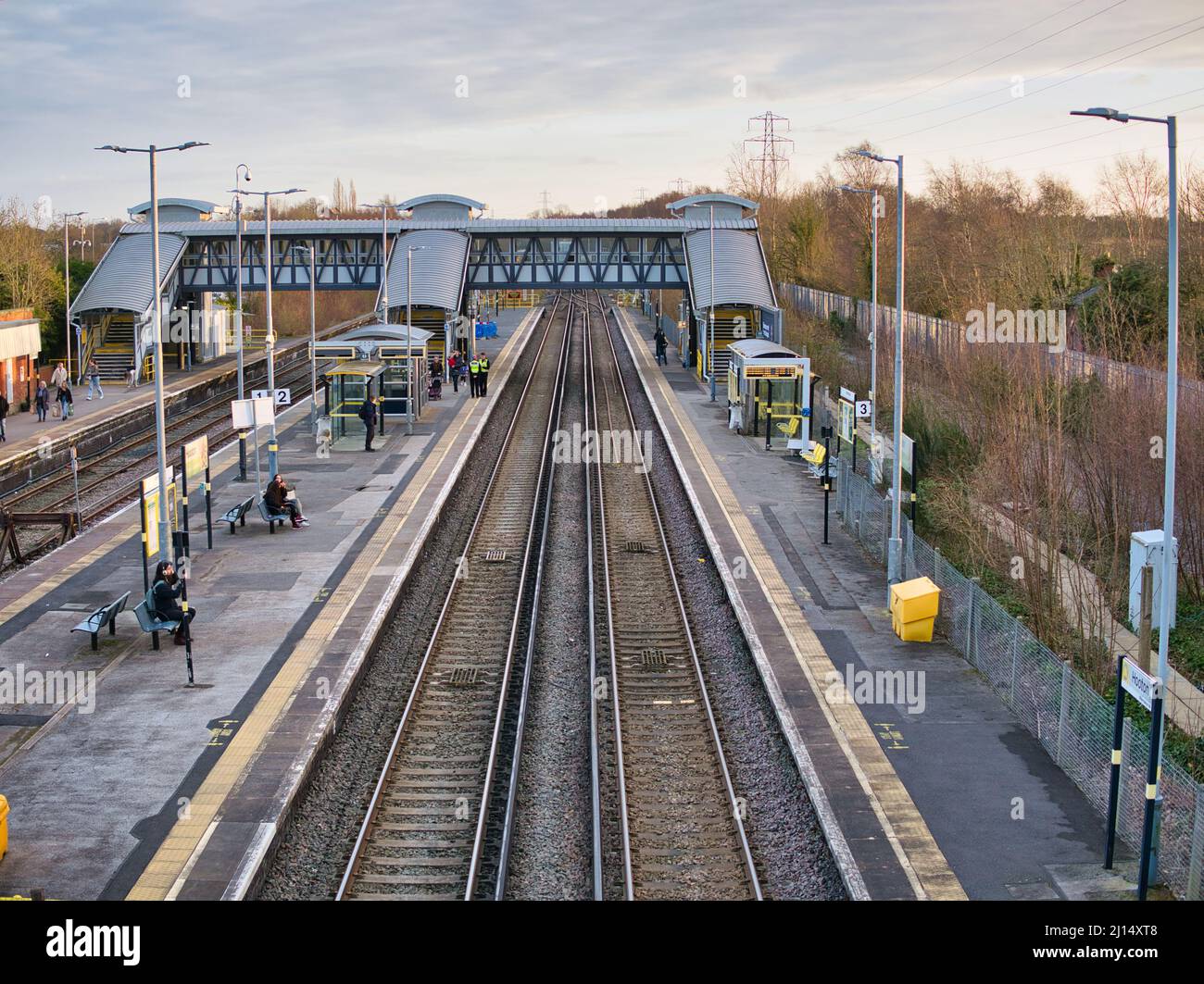 Voies ferrées et plates-formes à la gare de Hooton à Wirral, dans le nord-ouest de l'Angleterre. Les navetteurs et le personnel de sécurité attendent l'arrivée du prochain train. Banque D'Images
