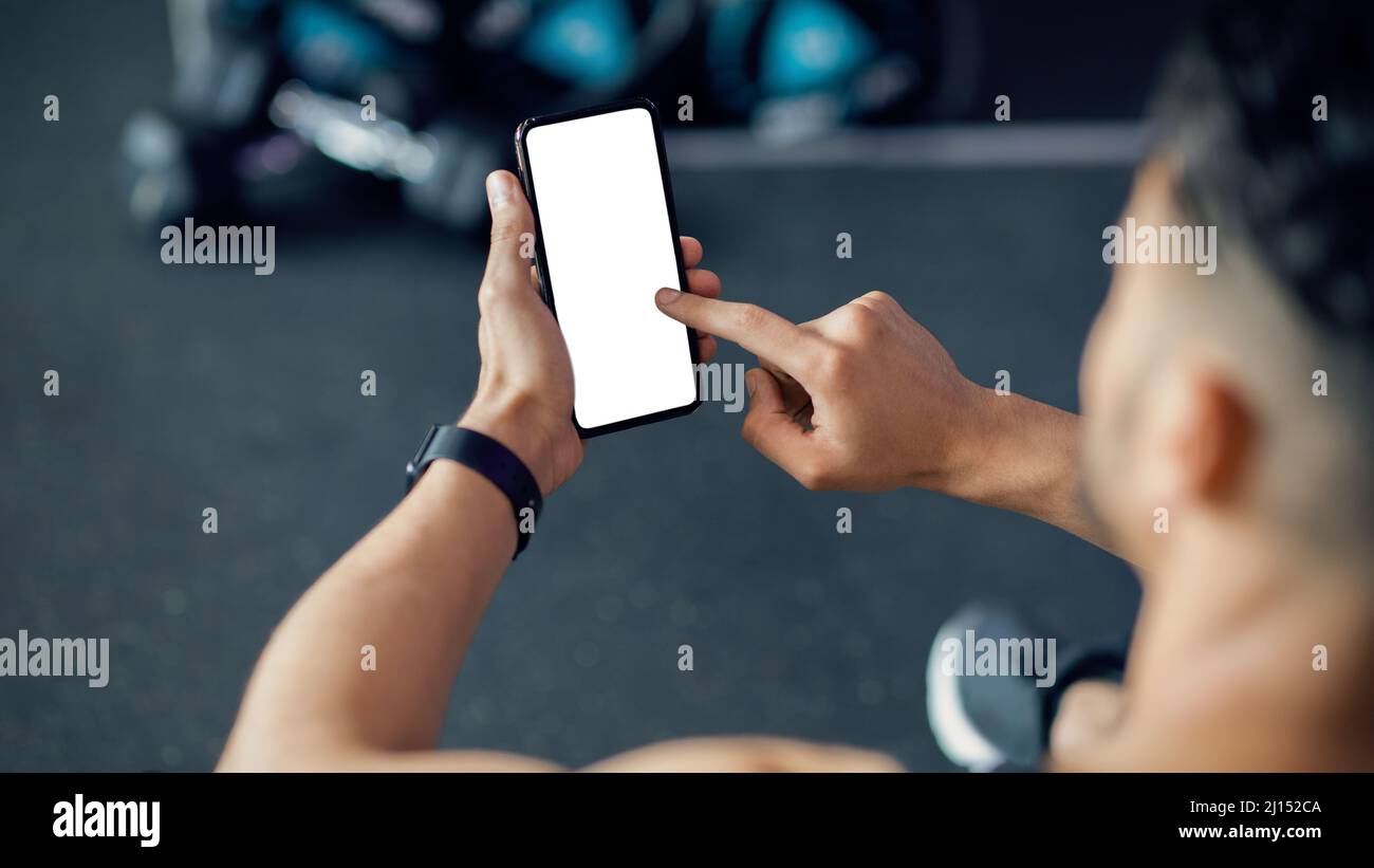 Homme méconnaissable utilisant un téléphone portable avec écran blanc à la salle de gym, Mockup Banque D'Images