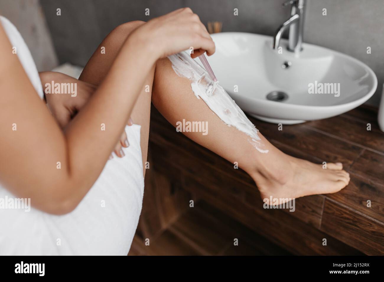 Femme non reconnaissable se raser les jambes dans la salle de bains, à l'aide d'un rasoir de sécurité, enlever les cheveux, faire l'épilation, la récolte, gros plan Banque D'Images