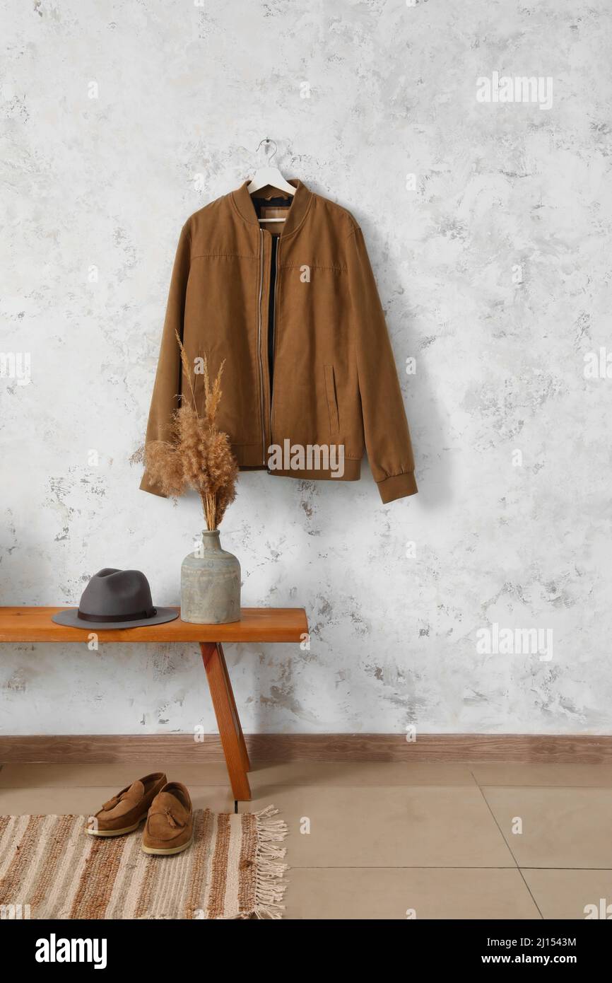 Banc en bois avec chapeau, vase, chaussures et veste accrochés au mur léger Banque D'Images