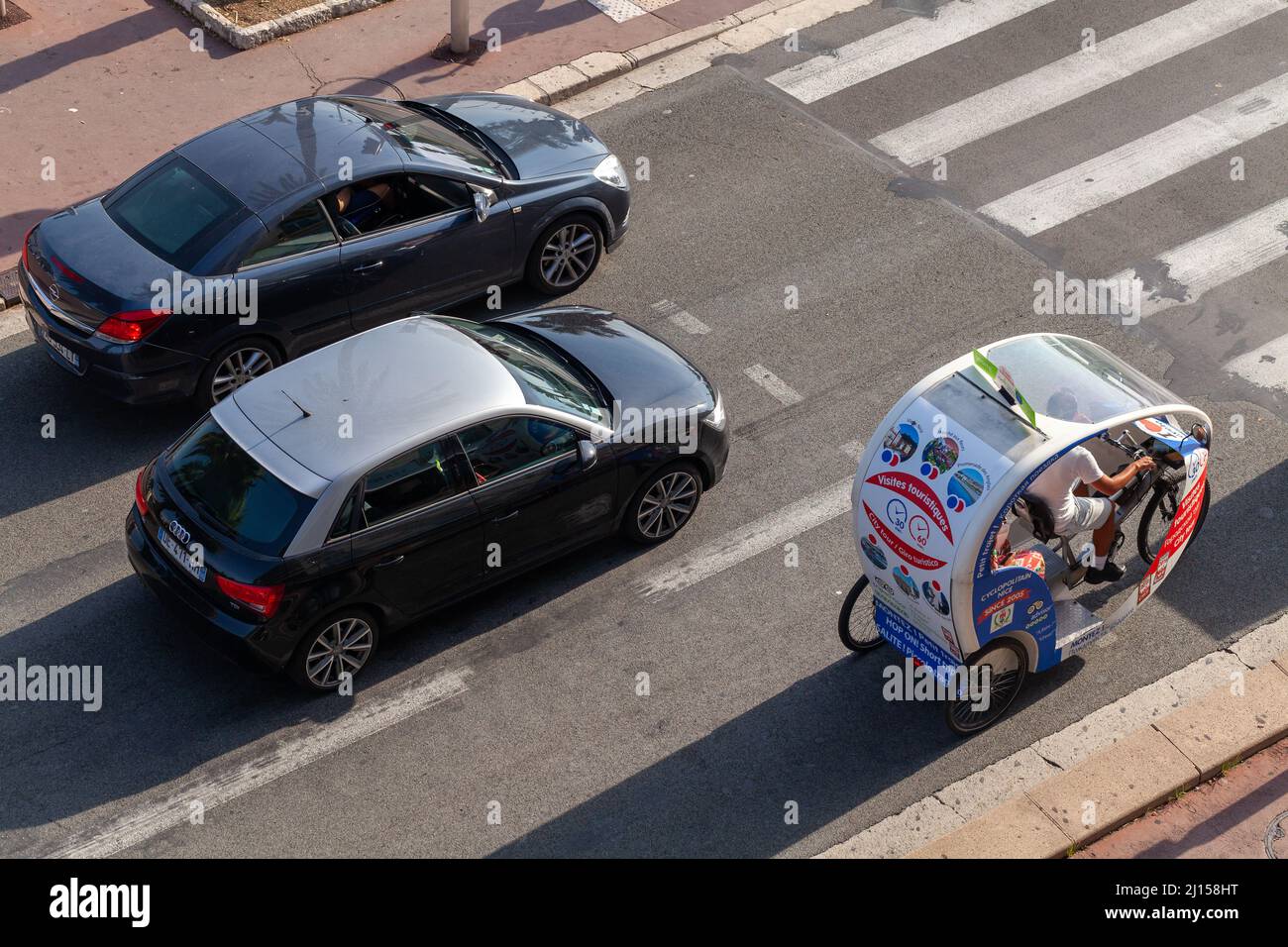 Nice, France - 13 août 2018: Voitures et touristes trishaw vélo sont sur la route par une journée ensoleillée Banque D'Images