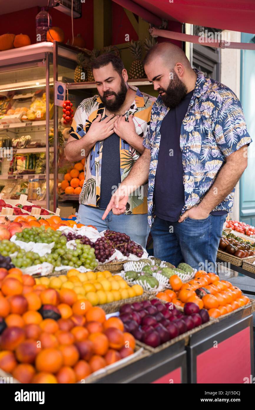 Jeunes couples gais de race blanche qui choisissent des fruits sur le marché. Concept de mode de vie sain. Banque D'Images