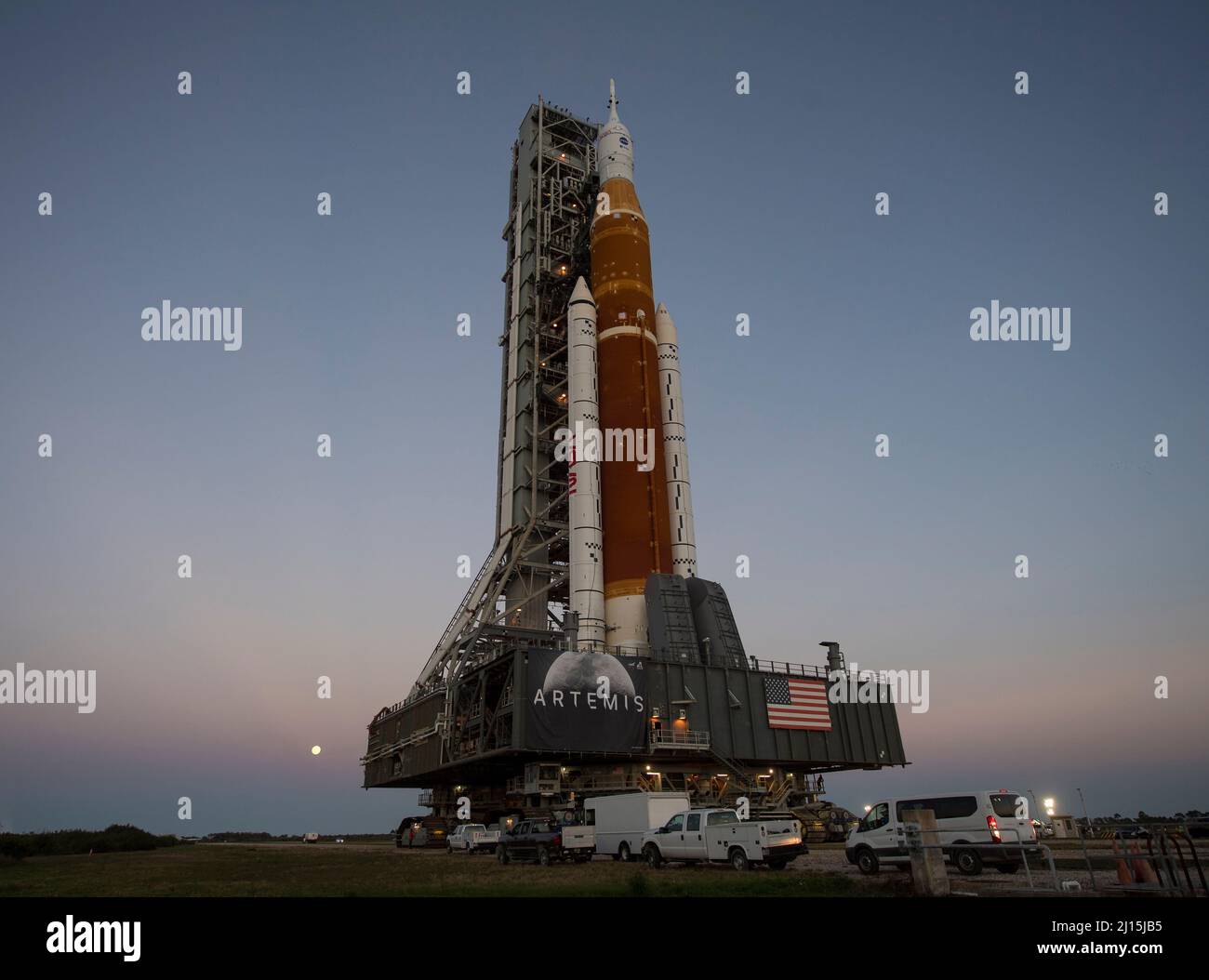 On voit la Lune se lever derrière la fusée SLS (Space Launch System) de la NASA avec le vaisseau spatial Orion à bord d'un lanceur mobile alors qu'elle se lance pour la première fois dans le complexe de lancement 39B, le jeudi 17 mars 2022, au Kennedy Space Center de la NASA en Floride. Avant l'essai en vol Artemis I de la NASA, la fusée SLS et l'engin spatial Orion entièrement empilés et intégrés feront l'objet d'une répétition en robe humide au Launch Complex 39B pour vérifier les systèmes et pratiquer les procédures de compte à rebours pour le premier lancement. Crédit photo : (NASA/Aubrey Gemignani) Banque D'Images