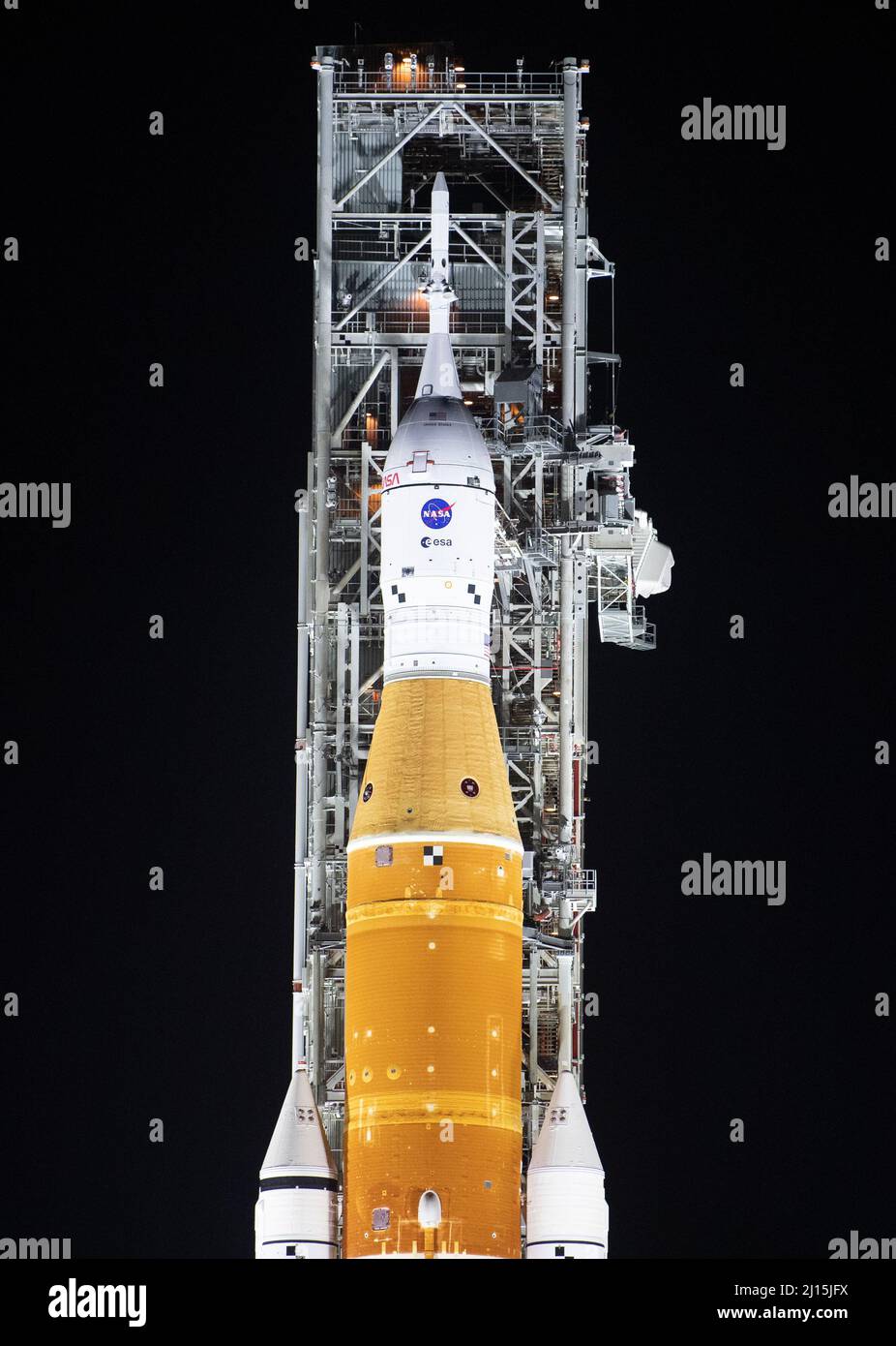 La fusée SLS (Space Launch System) de la NASA à bord de l'engin spatial Orion est illuminée par des projecteurs au sommet d'un lanceur mobile au Launch Complex 39B, le vendredi 18 mars 2022, après avoir été lancée pour la première fois sur le plateau de lancement au Kennedy Space Center de la NASA en Floride. Avant l'essai en vol Artemis I de la NASA, la fusée SLS et l'engin spatial Orion entièrement empilés et intégrés feront l'objet d'une répétition en robe humide au Launch Complex 39B pour vérifier les systèmes et pratiquer les procédures de compte à rebours pour le premier lancement. Crédit photo : (NASA/Joel Kowsky) Banque D'Images