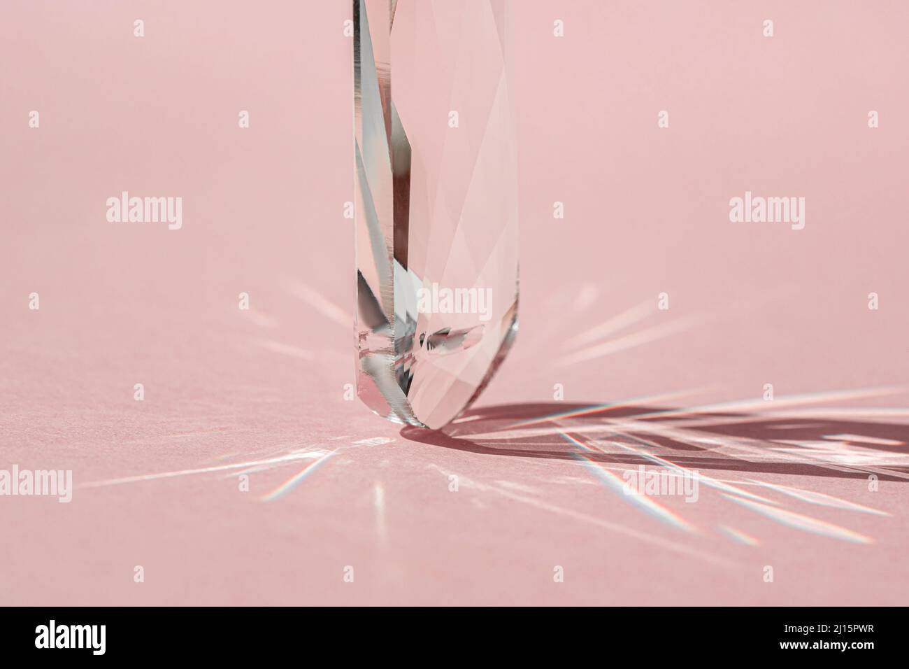 Prisme en cristal avec diffraction de la lumière des couleurs du spectre et réflexion avec lumière tendance et ombres dures sur fond rose. Spectre lumineux Banque D'Images