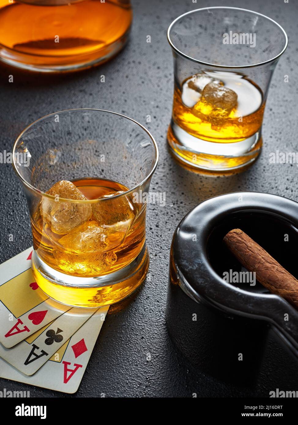 Deux verres de whisky avec glace, cigare dans un cendrier et cartes de poker. Jeu de poker, cigare et whisky concept. Banque D'Images