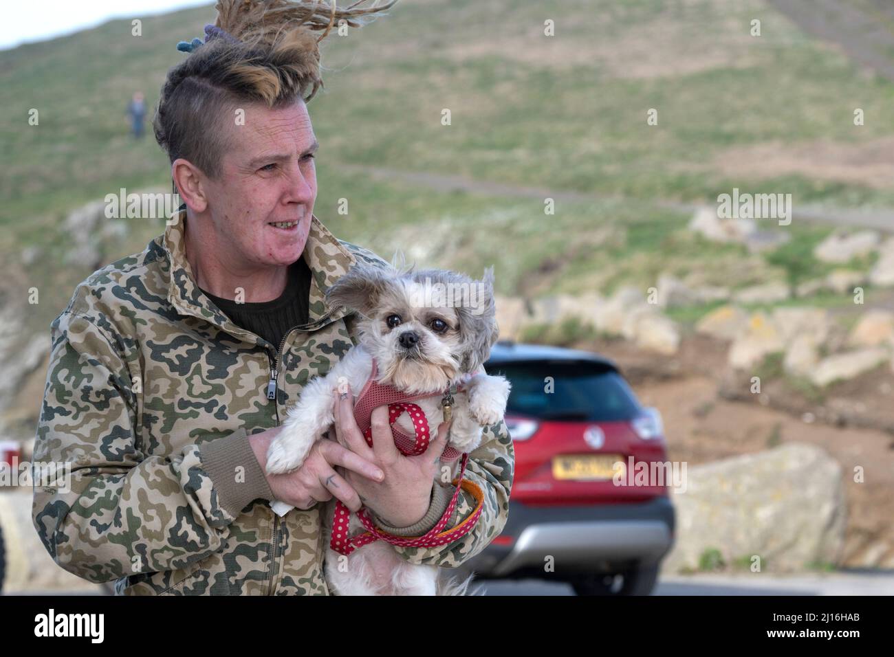 Un propriétaire de chien portant un petit chien. Banque D'Images