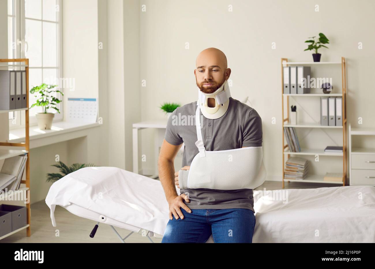 Triste homme avec un bras cassé dans une élingue et un collier de fixation  autour de son cou assis à l'hôpital Photo Stock - Alamy