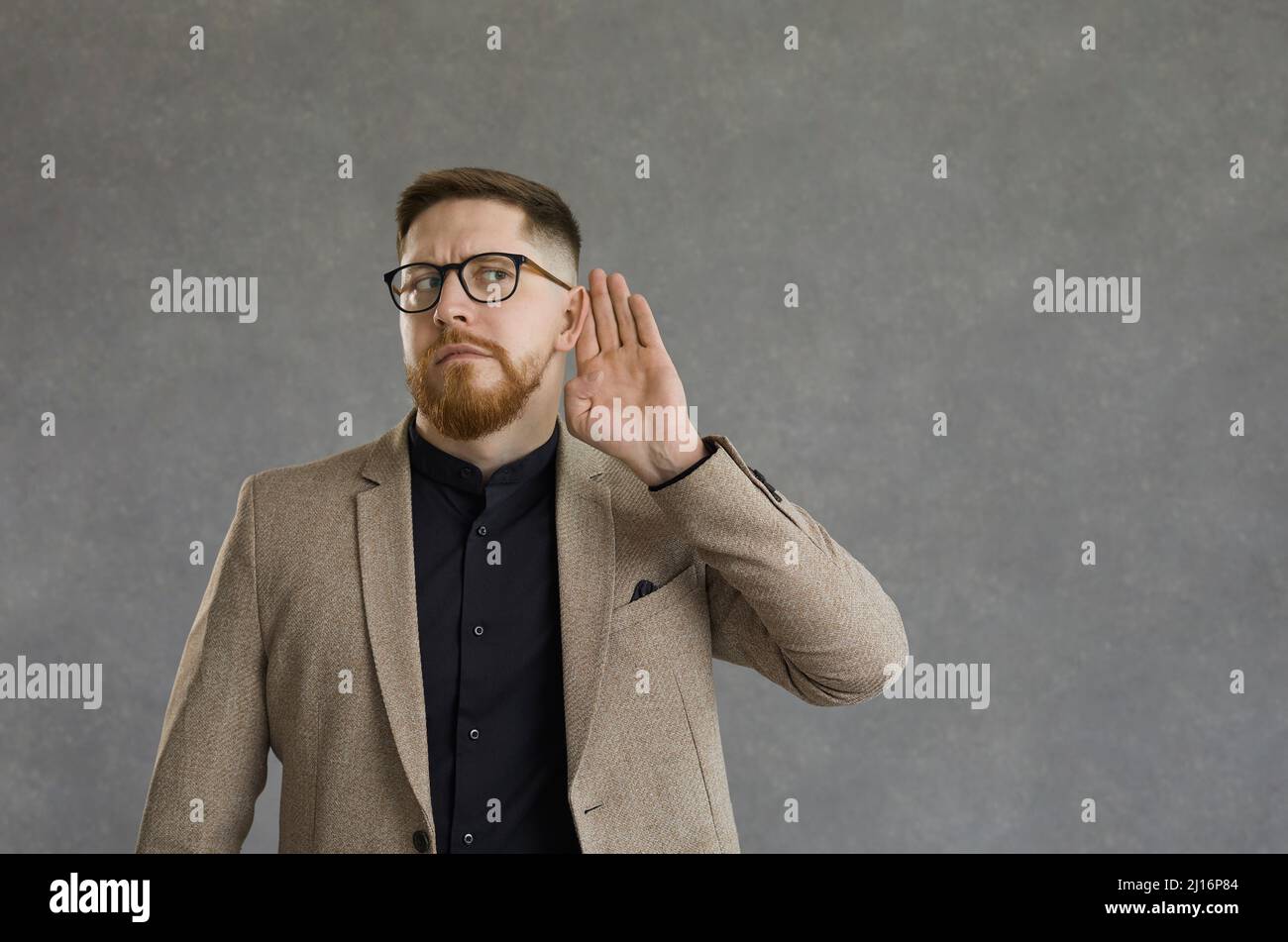 Un curieux homme avec une expression inquiète tient sa main à l'oreille en écoutant une conversation secrète. Banque D'Images