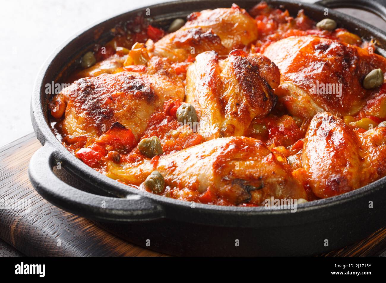 Morceaux de poulet cuits avec une sauce de tomates, poivrons, oignons et ail dans une poêle à frire sur la table. Horizontal Banque D'Images