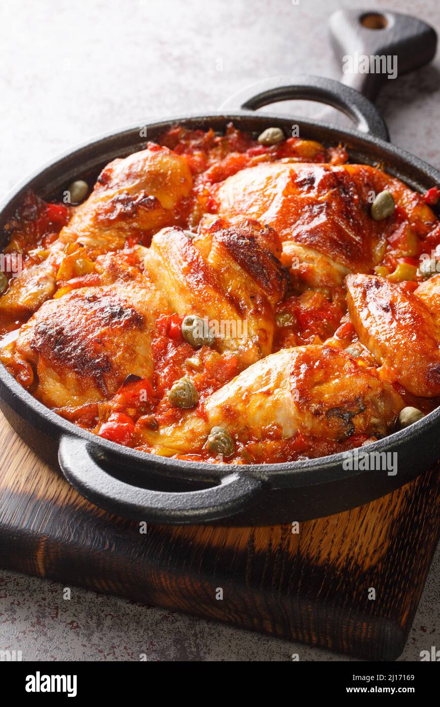 Poulet cuit à la sauce de légumes sofrito gros plan dans une poêle sur la table. Vertical Banque D'Images