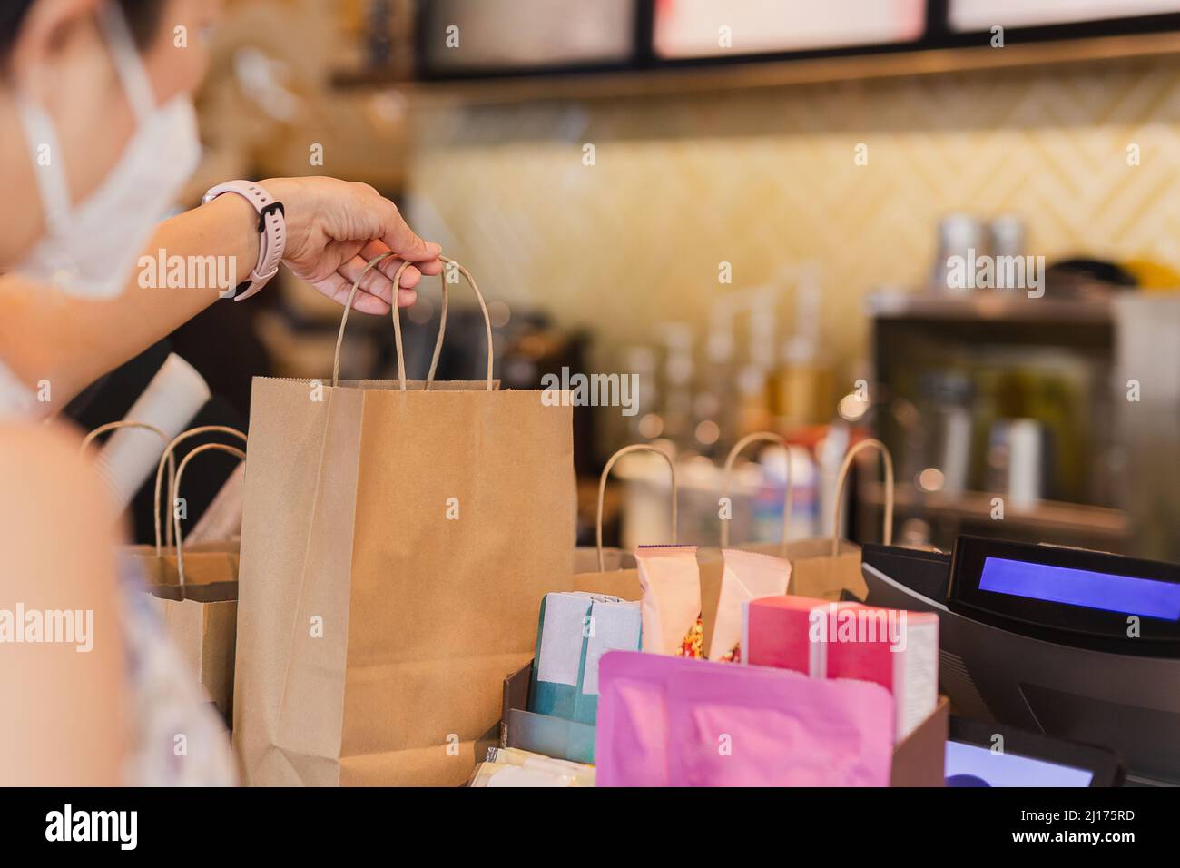 Serveuse au comptoir donnant eco friendly sac de papier avec boisson à emporter dans le café. Banque D'Images